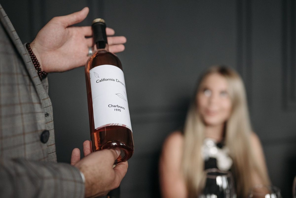 Homme offre une bouteille de vin à une femme dans un cadre élégant Homme offre une bouteille de vin à une femme dans un cadre élégant