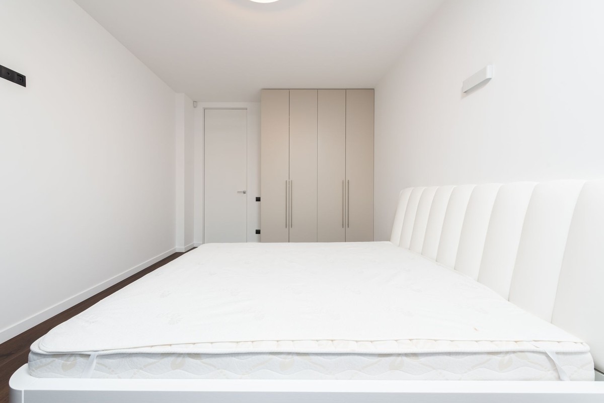 ALT: Chambre minimaliste avec lit, matelas, placard et porte